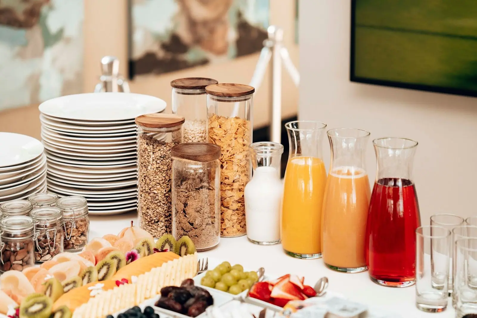 Mesa de desayuno buffet con cereales, jugos y fruta